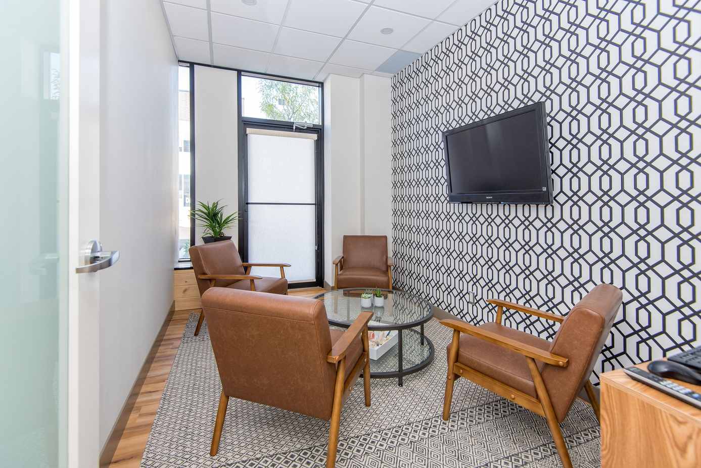 Willow Dental Associates consultation room with leather armchairs, TV and glass table in Mississauga, ON