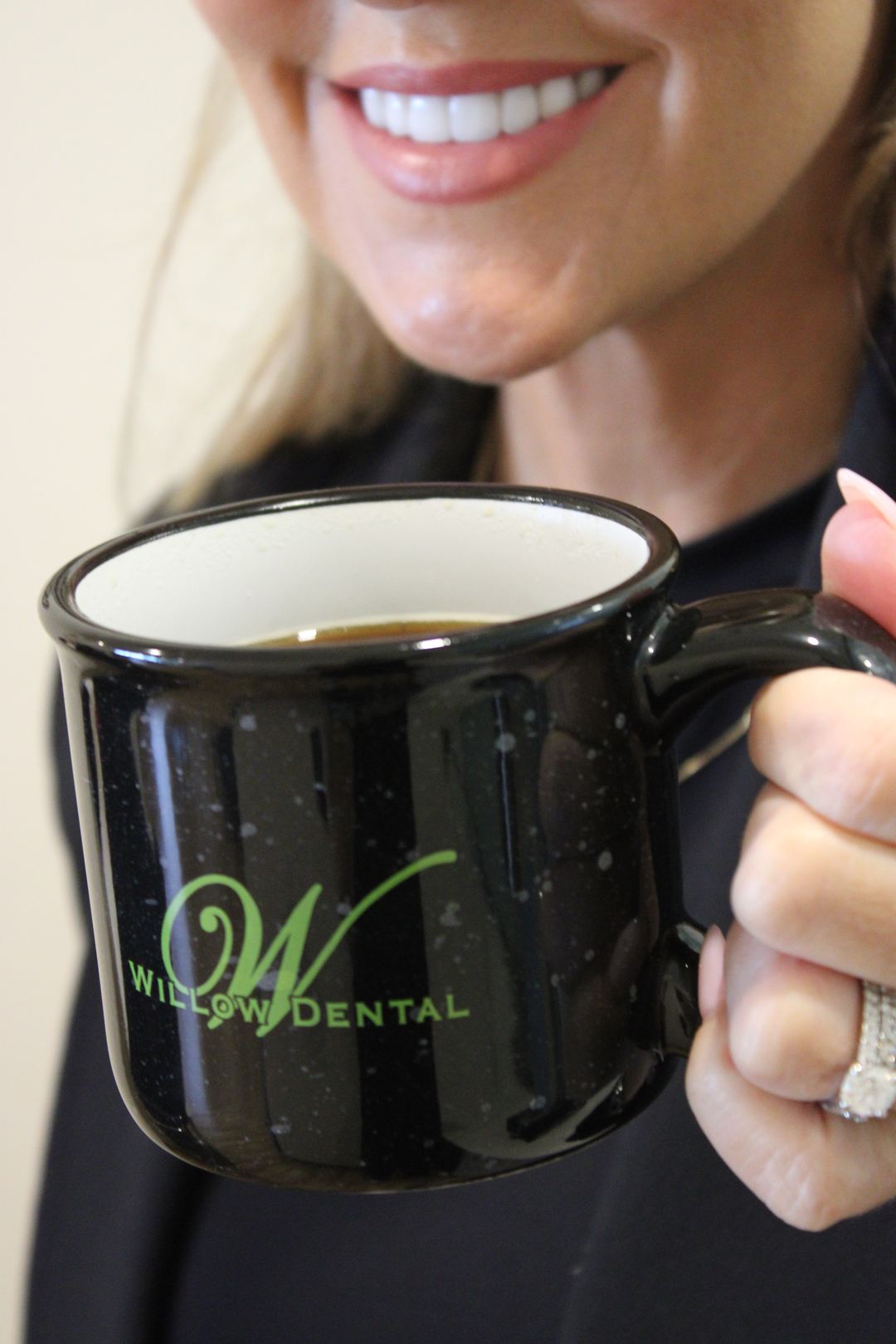 Willow Dental Associates smiling team member holding branded coffee mug, cropped at smile in Mississauga, ON